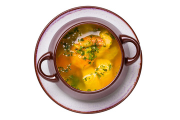 Seafood background. Macro of freshly cooked Mediterranean fish soup with salmon and shrimps in a brown ceramic bowl on plate isolated on a white background. Advertising. Top view.