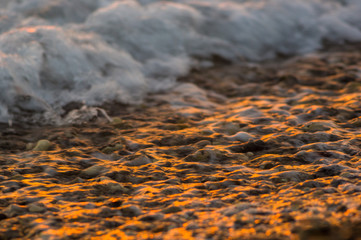 pebble stones on the sea beach, the rolling waves of the sea with foam