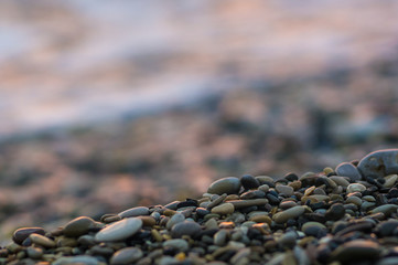 pebble stones on the sea beach, the rolling waves of the sea with foam