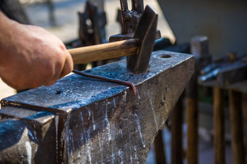 blacksmith performs the forging of hot glowing metal on the anvil