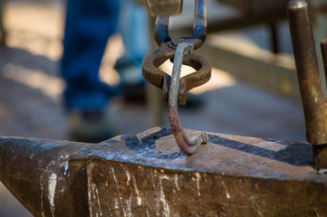 blacksmith performs the forging of hot glowing horseshoe on the anvil