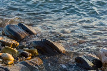 pebble stones on the sea beach, the rolling waves of the sea with foam