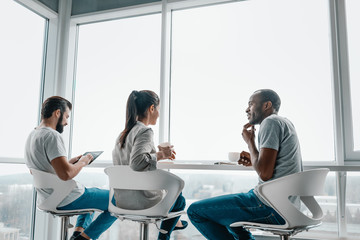 Multi-cultural colleagues are joking during coffee break at workplace