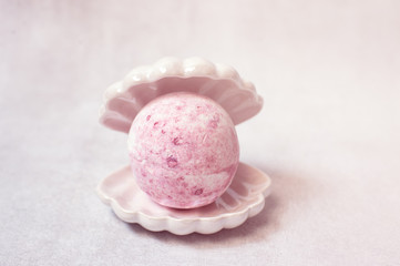 Spa still life, pink bath bomb in sea shell on white background