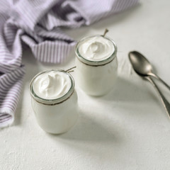 Two portions of fresh natural greek homemade organic yogurt in a glass jar.Greek yogurt in a glass jars with spoons.Top view.