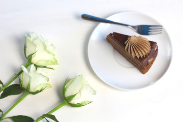 Three romance  white roses and piece of chocolate cake. Compliment congradulation for women. Celebration of happy birthday, anniversary, party