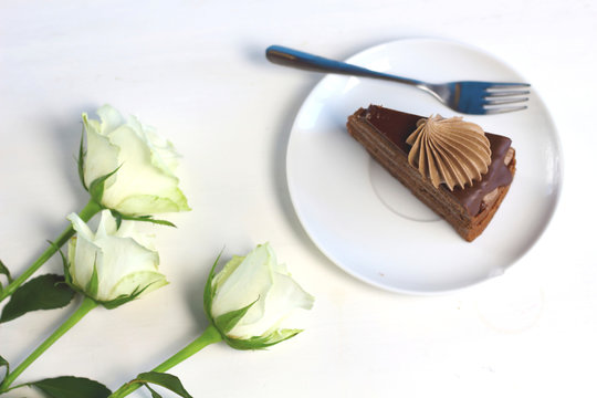 Three romance  white roses and piece of chocolate cake. Compliment congradulation for women. Celebration of happy birthday, anniversary, party