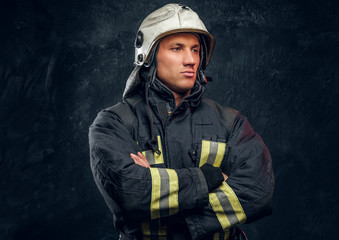 Brutal fireman in uniform posing for the camera standing with crossed arms and confident look....