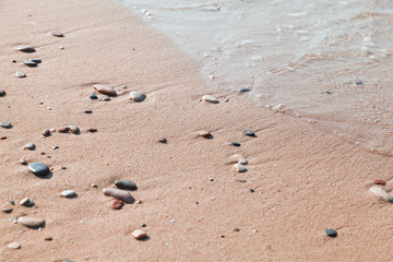 Small wet stones in sand on the beach