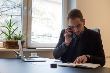 Naklejka premium businessman working on laptop in office taking notes