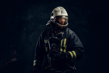 Manly firefighter in helmet looks sideways in studio on black background