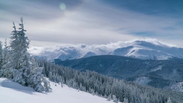 Time lapse of flowing clouds over winter Goverla mountain. Snow-covered Christmas tree in the foreground. Ukrainian Carpathians. 4K