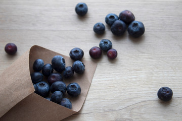 Fresh blueberry in kraft paper on wood background