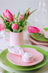 Happy easter. Decor and table setting of the Easter table is a vase with pink tulips and dishes of pink and green color.