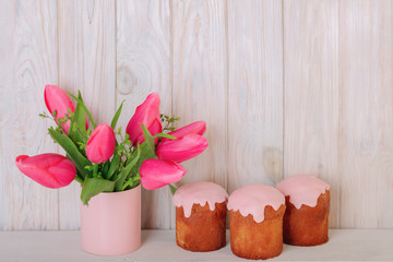 Happy easter. Decor and table setting of the Easter table is a vase with pink tulips and dishes of pink and green color.