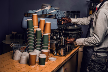 African barista n white shirt and apron makes coffee on coffee machine in a coffee shop