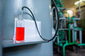 Red liquid in glass bottle. Metal pipe. Carbon dioxide production plant. Colorless gas. Gas...