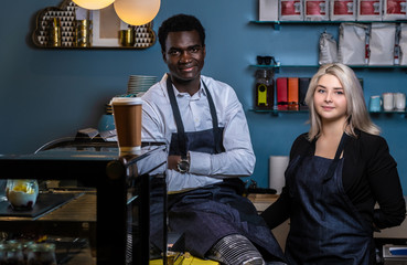 Two young multiracial baristas posing with a confident look in a coffee shop or cafe 