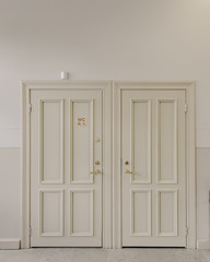 Interior of light public restroom with white wooden doors