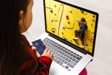 Little girl Hands holding credit card and using laptop.Online shopping in childhood.