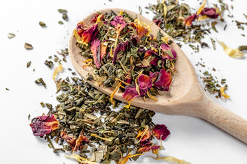 Green tea with dried flower petals and pieces of citrus on a wooden spoon. Dried tea for welding....