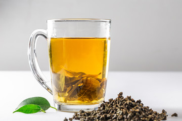 A Cup of green tea with dried large leaf tea and fresh tea leaves on a white background. Diet and healthy drink