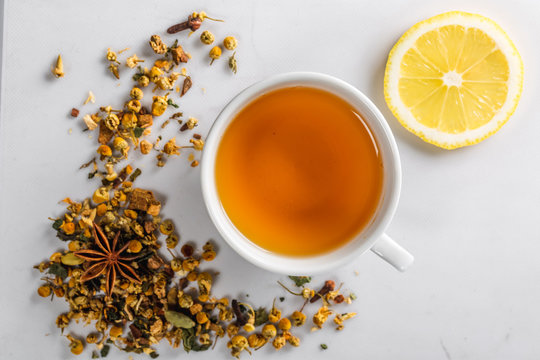 A Cup of green tea with dried chamomile flowers and a slice of cut lemon on a white background. Diet and healthy drink. Flatley. Top view