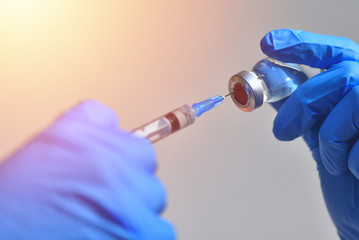 Closeup of vaccine bottle with syringe and needle for immunization on vintage medical background, medicine and drug concept