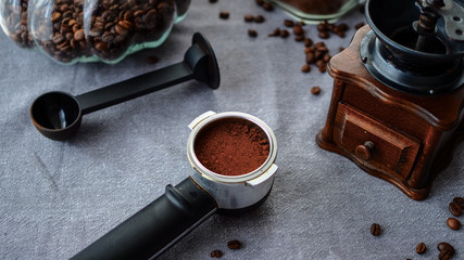 Świeżo zmielona kawa przygotowania do parzenia w otoczeniu młynka do kawy i ziarenek kawy.