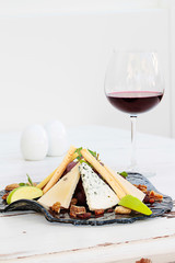 Various types of cheese on a plate and red wine