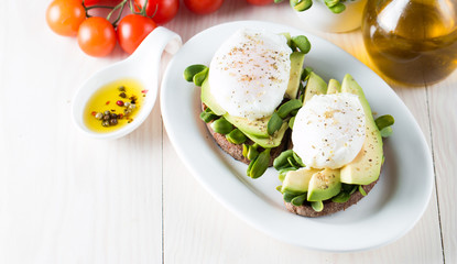 Avocado toast, cherry tomato on wooden background. Breakfast with toast avocado, vegetarian food, healthy diet concept. Healthy sandwich with avocado and poached eggs.