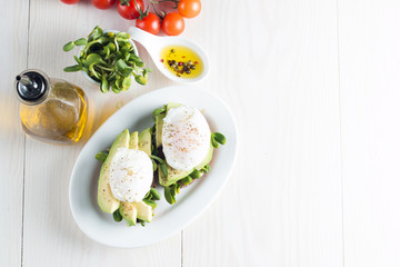 Avocado toast, cherry tomato on wooden background. Breakfast with toast avocado, vegetarian food, healthy diet concept. Healthy sandwich with avocado and poached eggs.