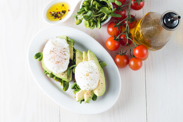 Avocado toast, cherry tomato on wooden background. Breakfast with toast avocado, vegetarian food, healthy diet concept. Healthy sandwich with avocado and poached eggs.