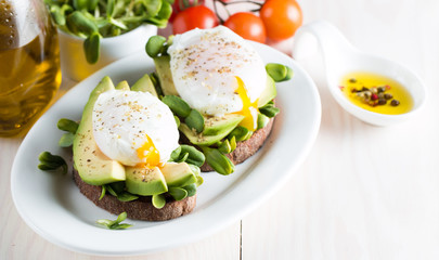 Avocado toast, cherry tomato on wooden background. Breakfast with toast avocado, vegetarian food, healthy diet concept. Healthy sandwich with avocado and poached eggs.