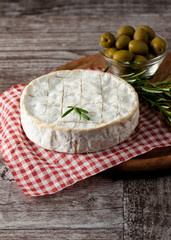 Brie type of cheese. Camembert cheese. Fresh Brie cheese and a slice on a wooden board with nuts, honey and leaves. Italian, French cheese.