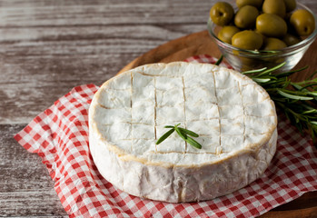 Brie type of cheese. Camembert cheese. Fresh Brie cheese and a slice on a wooden board with nuts, honey and leaves. Italian, French cheese.