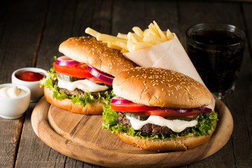Close-up photo of home made hamburger with beer made of beef, onion, tomato, lettuce, cheese and spices. Fresh burger closeup on wooden rustic table with potato fries and chips.