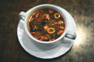 Saltwort soup with olives in a white bowl on a table...