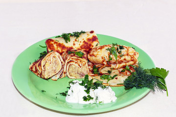 pancakes with a filling of a mixture of potatoes and meat on a green plate