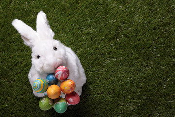 Cute white bunny holding a bunch of Easter eggs