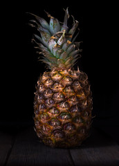 Pineapple on black isolated background on old rustic desk.