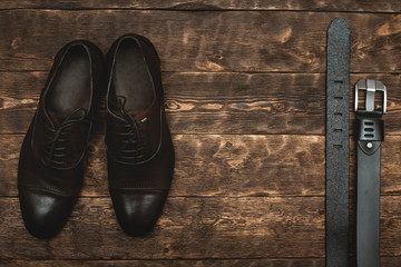 Male belt and a elegant shoes on a brown wooden floor background with copy space.