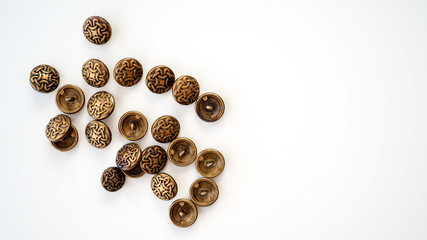 Metalowe guziki. Złote, srebrne, ciemne guziki leżące na białym tle