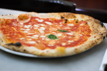 Neapolitan Pizza Margherita On A Tray On A Table In A Restaurant in Naples, Italy.