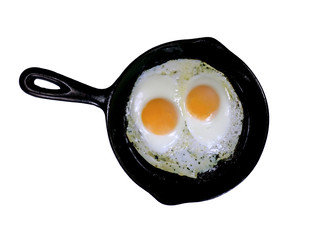 Two eggs, sunny side up in a small cast iron frying pan, isolated on white.