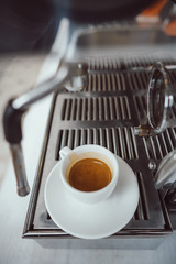 close-up view of glass cup with cappuccino and coffee machine
