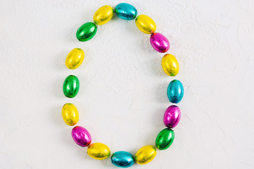 Colorful Easter egg of chocolate candies small eggs on white concrete background