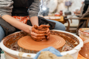 Craftsman hands making pottery bowl. Woman working on potter wheel . Family business shop sculpts pot from clay view top.