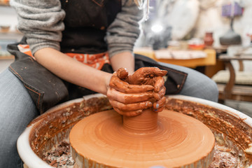Craftsman hands making pottery bowl. Woman working on potter wheel . Family business shop sculpts pot from clay view top.