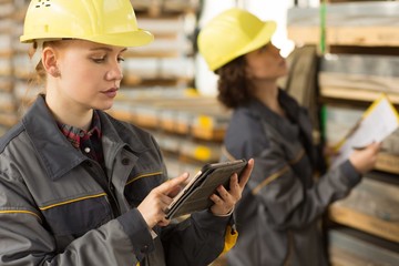 Cute female worker using laptop and seriously looking at screen in warehouse.